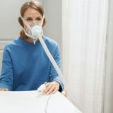 Woman using breathing therapy medical device in clinic