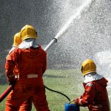 fire fighter team on training fight with gas and oil spray turbulence water to distinguished fire