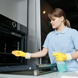 Woman cleaning the oven in the kitchen
