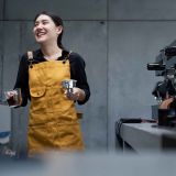 smiling-barista-in-yellow-apron-preparing-coffee-i-2025-02-20-01-31-34-utc