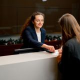 a smiling receptionist helping a guest to fill out registration form at the hotel