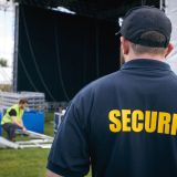 Rear View Of Security Team At Outdoor Stage For Music Festival Or Concert