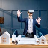 Elegant man as an architect or client imagining architectural project with virtual reality glasses standing at the working place in the luxury office