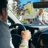 car driver waiting while young woman crossing road