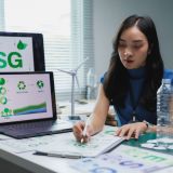 Esg analyst analyzing environmental data on a laptop, preparing detailed sustainability reports to drive corporate responsibility and ethical investment strategies