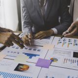 Financial analyst analyzes business finance reports on laptop and graph documents during corporate meeting discussions showing successful teamwork, business meeting ideas, marketing.