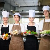 Group of culinary students proudly holding fresh vegetables, ready for their cooking class.