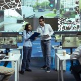 Indian team of operators instructing their colleagues to use CCTV surveillance footage and guide couriers in traffic. Employees operating with global positioning system in satellite map.