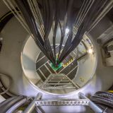 Interior of a modern wind turbine mast. A metal hull is installed with big bundles of cables ladder and safety features.