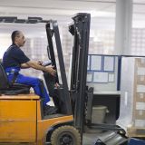 Mature man using forklift truck in factory