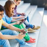 Group of friends using modern gadgets outside