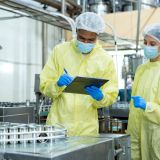 Quality control officers, dressed in protective gear, inspect the canned fish production line under strict food safety and hygiene standards at the canned fish factory