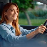 Smiling woman enjoying on a road trip while driving a car.
