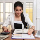 Business woman accountant or banker using calculator in retro office. Savings, finances and economy concept.