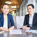 Cheerful business partners posing for photography with toothy smiles while having productive meeting at modern restaurant