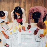 High angle shot of a diverse team of engineers having a meeting at workplace with building plans on a table. Multiracial group of architects working together and making creative solution for a project