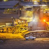 Caterpillats detail view of a giant Bucket Wheel Excavator next to a pickup truck at night
