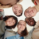 Low angle view of teenagers embracing while standing in the circle and looking at camera