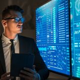The businessman man with tablet in his hands standing near blue screens
