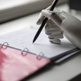 artificial robotic arm write down some notes with pen