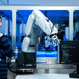 Meeting asian Engineers Maintenance Robot Arm at Lab. they are in a High Tech Research Laboratory with Modern Equipment. smiling multicultural businesspeople looking at camera while standing near robot.