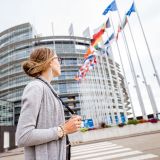 Young woman tourist standing with photo camera in front of the European parliament building in Strasbourg, France